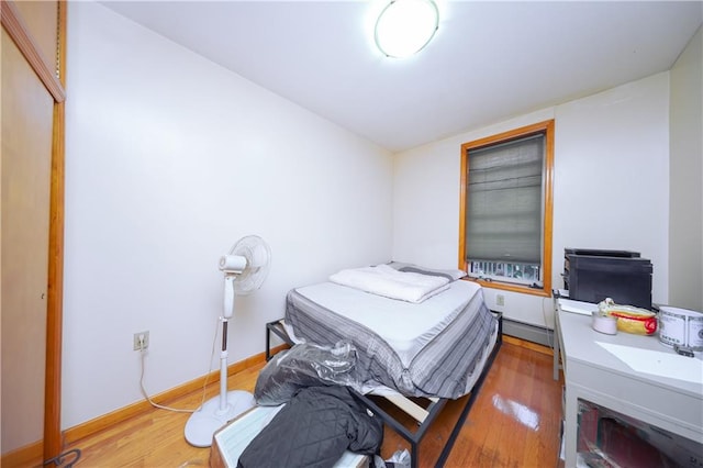 bedroom with a baseboard heating unit and hardwood / wood-style flooring