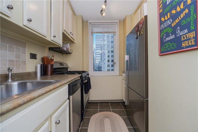 kitchen featuring stainless steel appliances, white cabinetry, dark tile patterned floors, and sink