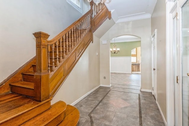 stairs with crown molding and a notable chandelier