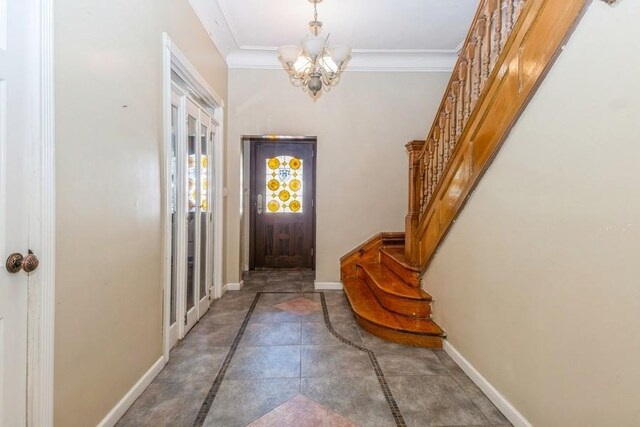 entryway featuring a notable chandelier and ornamental molding