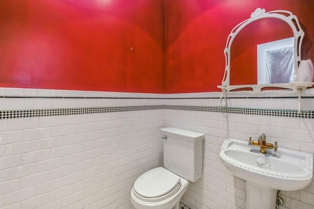 bathroom featuring tile walls, sink, and toilet