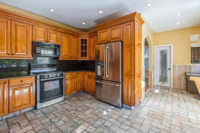 kitchen with dark stone counters, stainless steel appliances, and tasteful backsplash