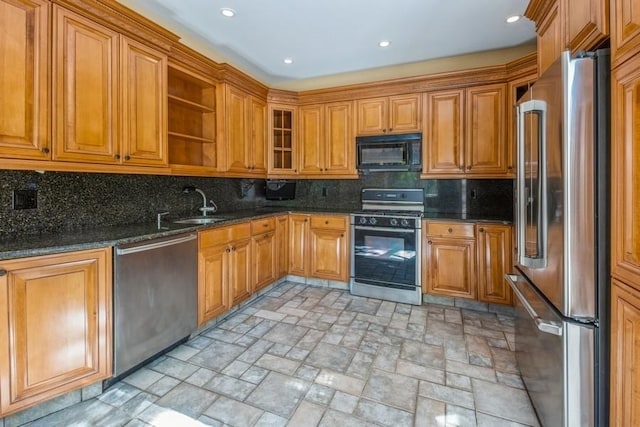 kitchen with dark stone countertops, stainless steel appliances, decorative backsplash, and sink