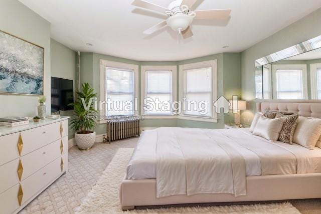 carpeted bedroom featuring multiple windows, radiator heating unit, and ceiling fan