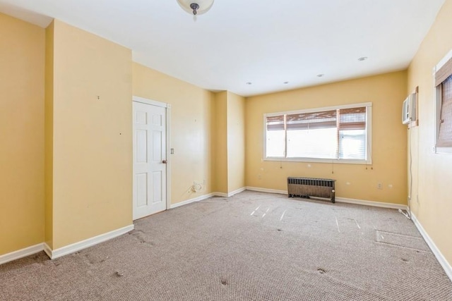 empty room with a wall mounted air conditioner, carpet flooring, and radiator