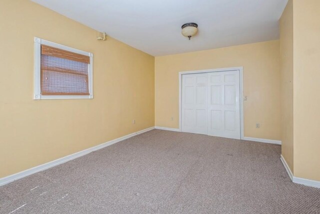 unfurnished bedroom with light colored carpet and a closet