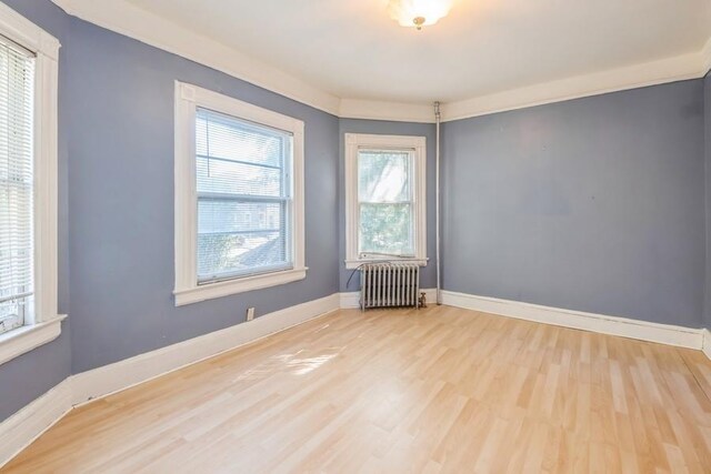 empty room featuring radiator heating unit and light wood-type flooring