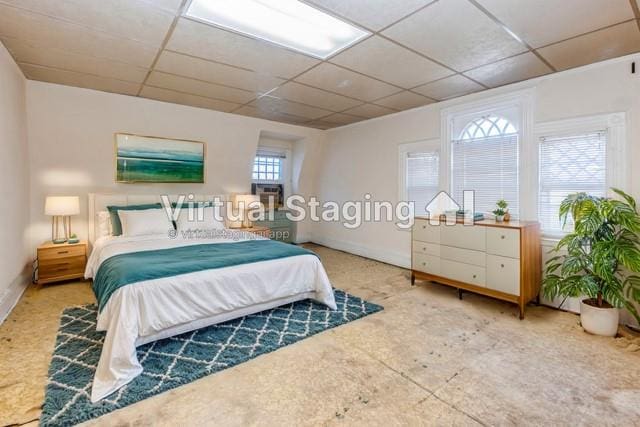 bedroom featuring multiple windows and a drop ceiling