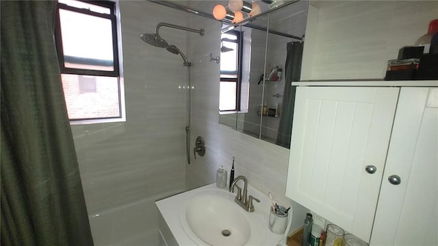 bathroom with sink, a shower with shower curtain, tasteful backsplash, and a healthy amount of sunlight