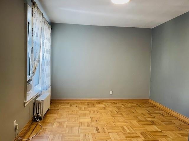 spare room featuring radiator and light parquet floors