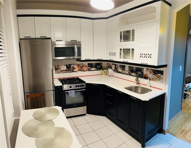 kitchen with light wood-type flooring, stainless steel appliances, white cabinetry, and sink