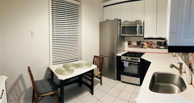 kitchen with light tile patterned floors, stainless steel appliances, white cabinetry, and sink