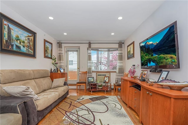 living room featuring light wood-type flooring, a wall mounted AC, and a baseboard radiator