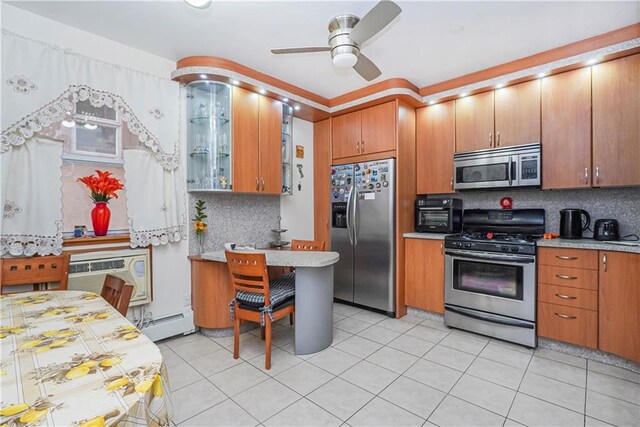 kitchen with light tile patterned flooring, a wall unit AC, stainless steel appliances, and tasteful backsplash