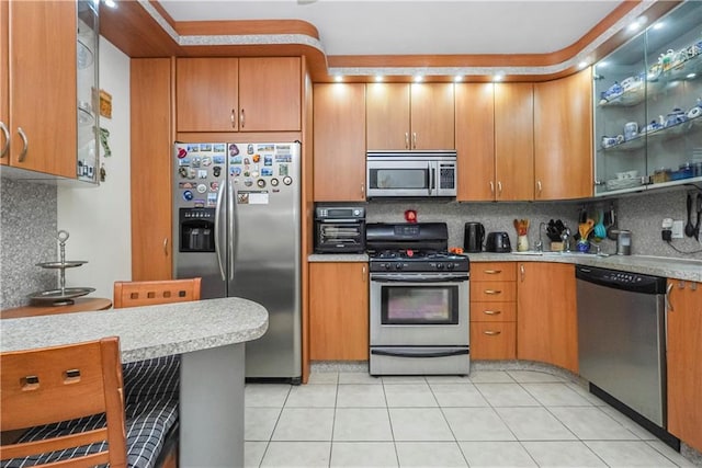 kitchen with light tile patterned floors, backsplash, a kitchen breakfast bar, and stainless steel appliances