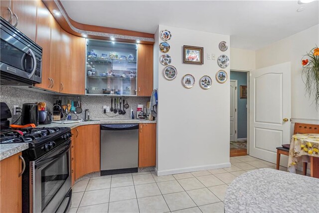 kitchen with light tile patterned floors, appliances with stainless steel finishes, and tasteful backsplash