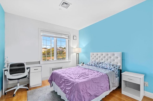 bedroom featuring radiator heating unit and light hardwood / wood-style flooring