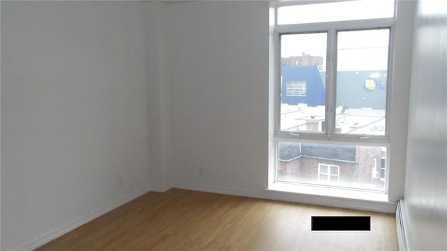 unfurnished room with light hardwood / wood-style flooring and a baseboard heating unit