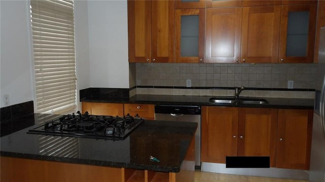 kitchen featuring sink, dark stone countertops, backsplash, and black gas cooktop