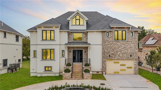 french country style house featuring stone siding, concrete driveway, a garage, a front yard, and stucco siding