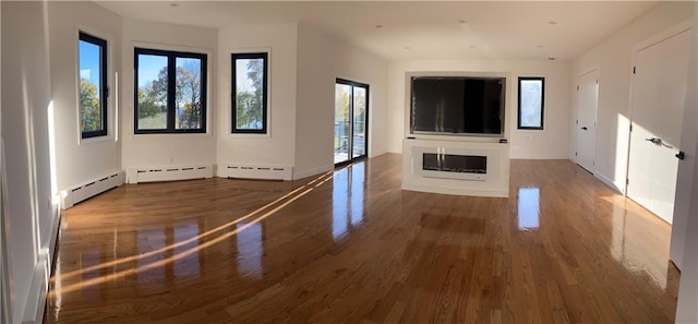 unfurnished living room with a glass covered fireplace, a baseboard radiator, and wood finished floors