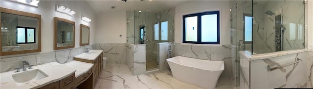 full bath featuring vanity, a wainscoted wall, a marble finish shower, a soaking tub, and marble finish floor