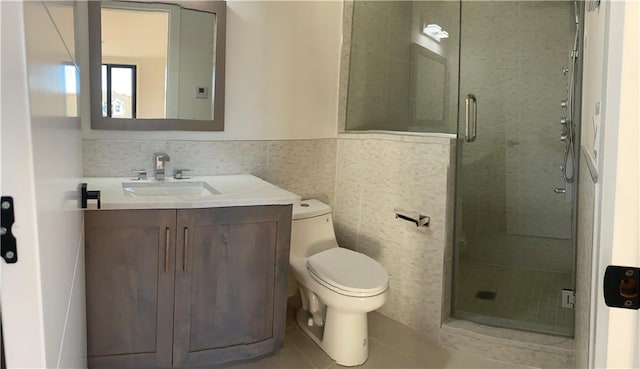 bathroom with a shower stall, toilet, tile walls, vanity, and tile patterned flooring