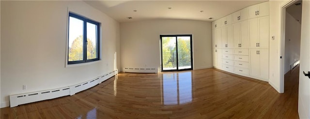 unfurnished bedroom featuring access to outside, vaulted ceiling, a baseboard heating unit, and wood finished floors