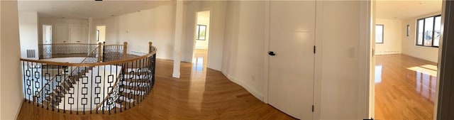 hallway featuring an upstairs landing, wood finished floors, and a baseboard radiator