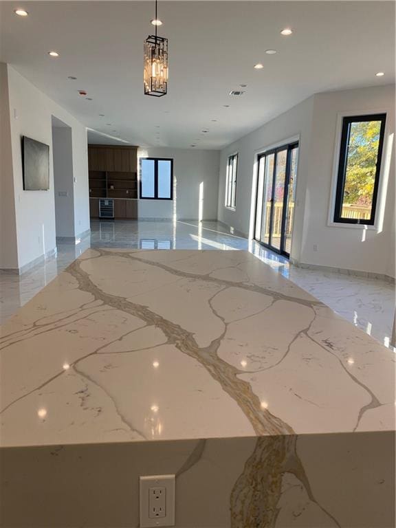 spare room featuring recessed lighting, a wealth of natural light, marble finish floor, and baseboards