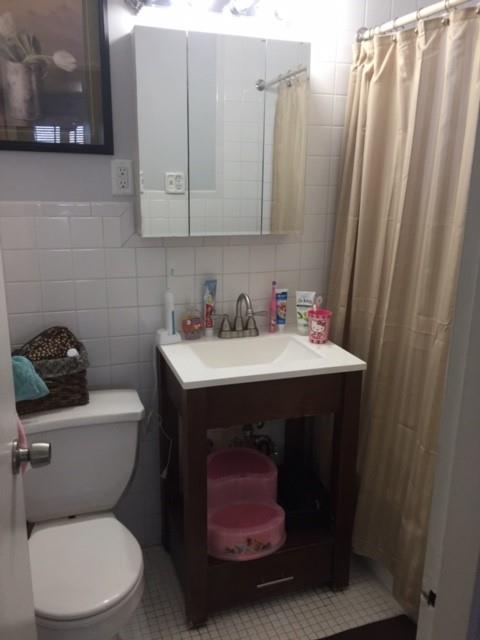 bathroom with toilet, tile walls, vanity, and walk in shower