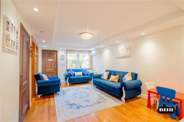 living room with a raised ceiling and hardwood / wood-style floors