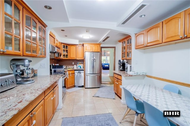 kitchen featuring light stone countertops, light tile patterned flooring, and appliances with stainless steel finishes