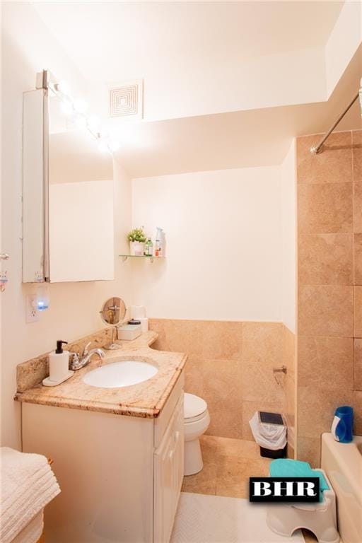 full bathroom with  shower combination, tile walls, tile patterned flooring, vanity, and toilet