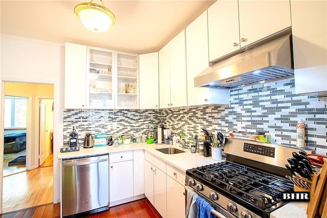 kitchen with tasteful backsplash, appliances with stainless steel finishes, white cabinets, and range hood