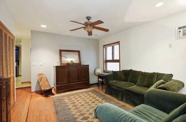 living room featuring ceiling fan, radiator, a wall unit AC, and light wood-type flooring