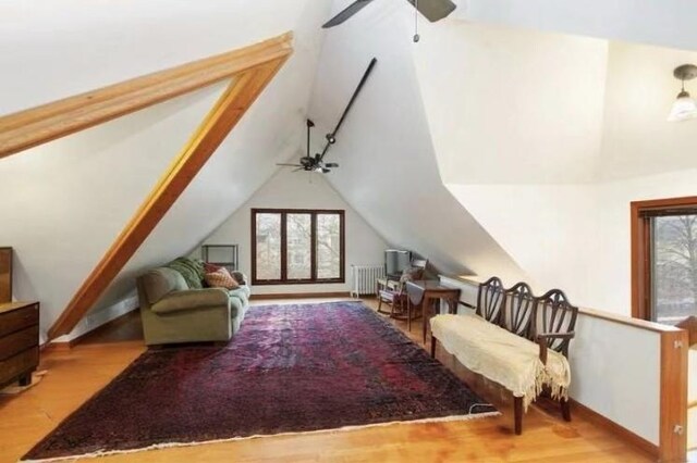 interior space featuring lofted ceiling, radiator heating unit, ceiling fan, and light hardwood / wood-style floors