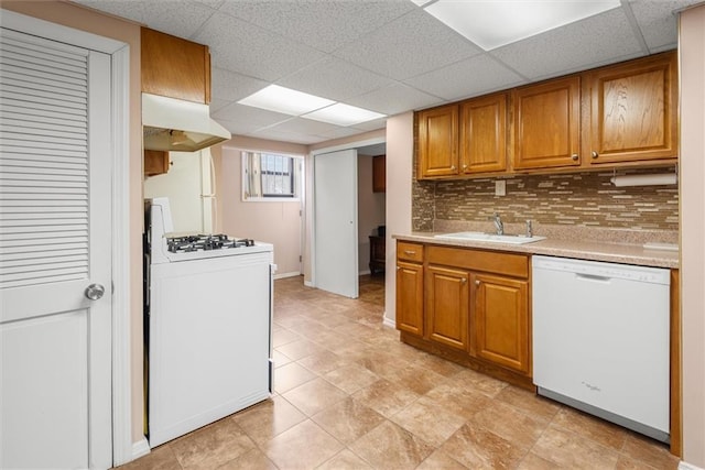 kitchen with sink, white appliances, a paneled ceiling, decorative backsplash, and light tile patterned floors