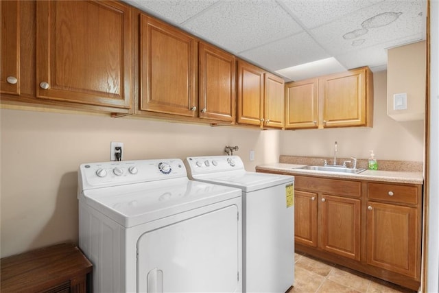 laundry area with washer and clothes dryer, sink, light tile patterned floors, and cabinets