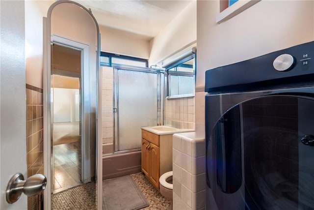 full bath with washer / clothes dryer, tile patterned floors, vanity, enclosed tub / shower combo, and tile walls