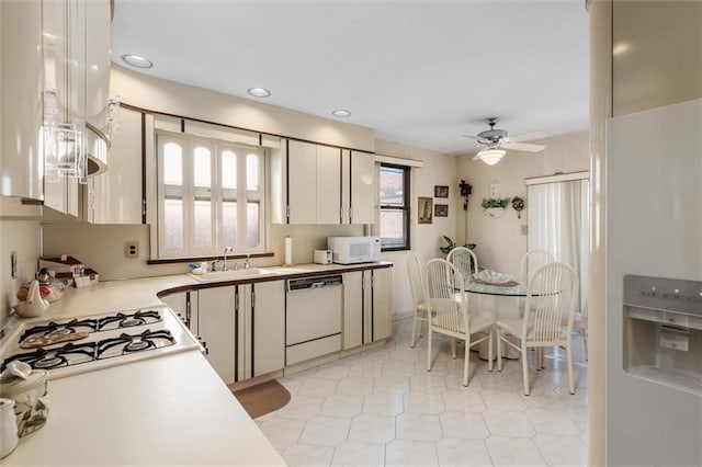 kitchen with white appliances, a sink, ceiling fan, light countertops, and light tile patterned floors