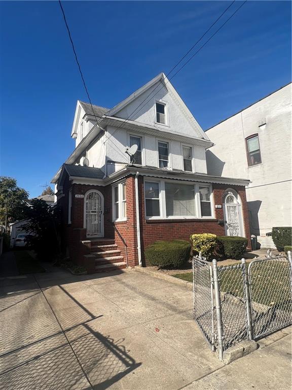 view of front facade featuring a fenced front yard, a gate, brick siding, and driveway