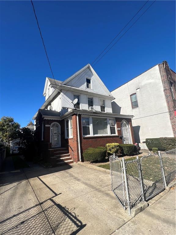 view of front of property featuring driveway, a fenced front yard, a gate, and brick siding