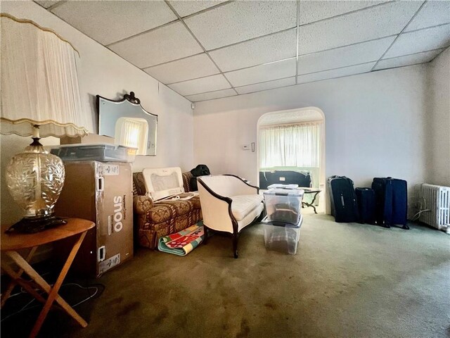 living area featuring a paneled ceiling, carpet flooring, and radiator