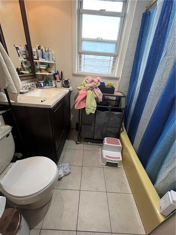 full bathroom featuring vanity, shower / bathtub combination with curtain, tile patterned floors, and toilet