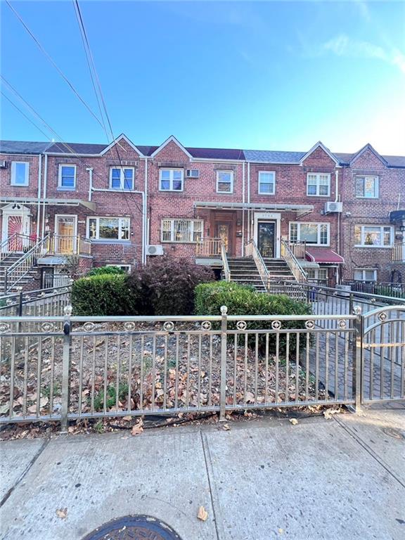 multi unit property with brick siding and a fenced front yard