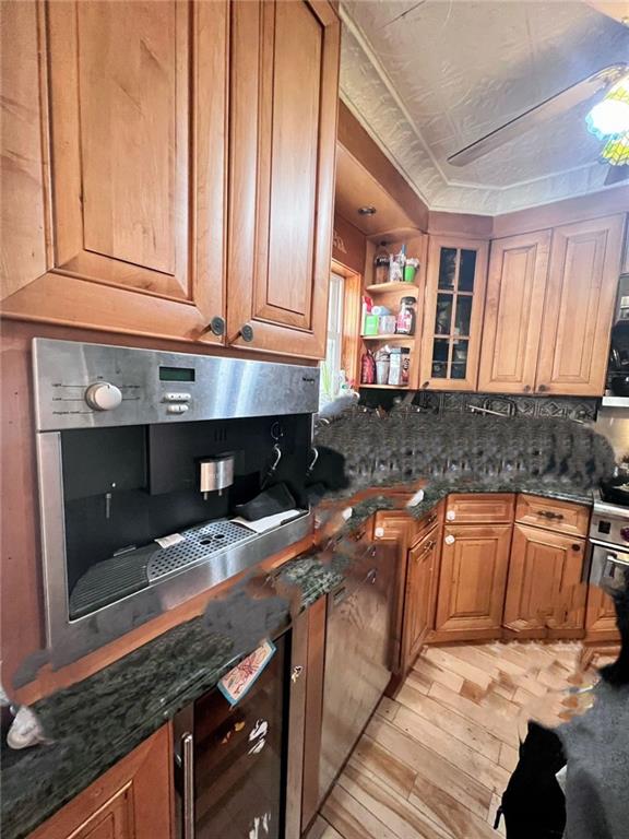 kitchen with dark stone countertops, decorative backsplash, light hardwood / wood-style floors, and stainless steel range oven