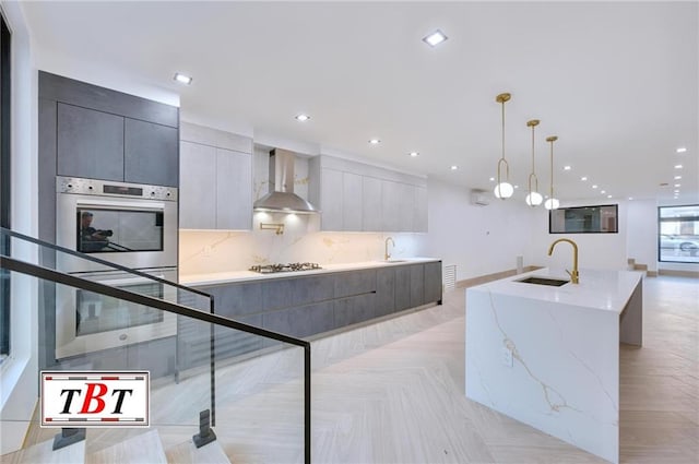 kitchen featuring sink, decorative light fixtures, light parquet floors, and wall chimney range hood