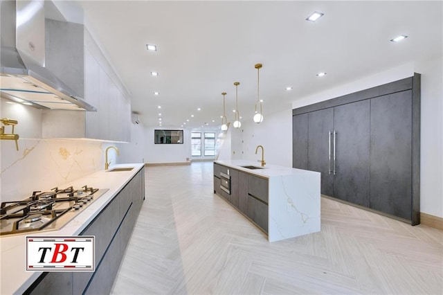 kitchen featuring pendant lighting, stainless steel gas stovetop, wall chimney exhaust hood, and sink