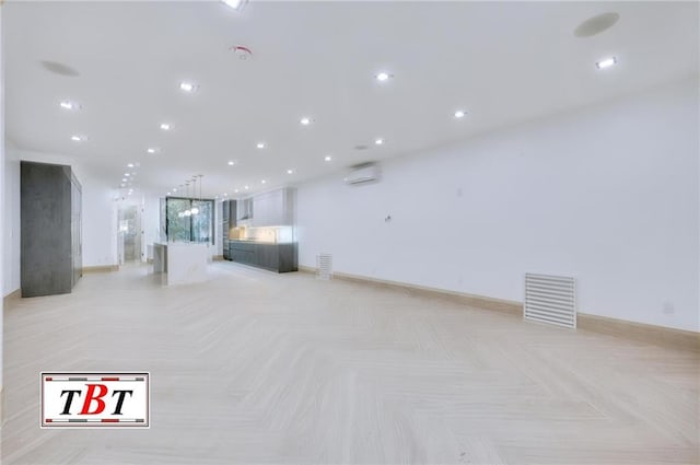 unfurnished living room featuring a wall mounted air conditioner and light parquet floors